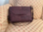 Front of brown cork bag sitting on couch, strap is adjustable