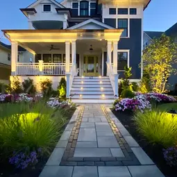 Large house with expertly installed illuminated porch, walkway, and landscaped garden at dusk. | Down To Earth Landscaping | Jackson New Jersey, USA (732) 833-7702