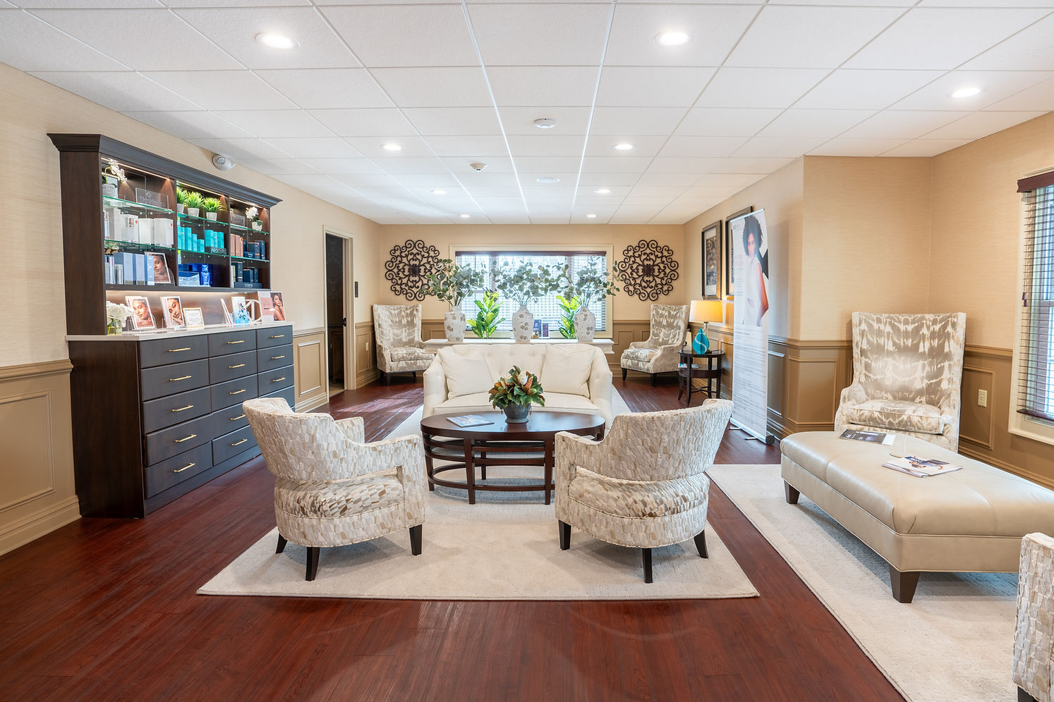 Elegant waiting room with plush seating, dark wood floor, product display cabinet.