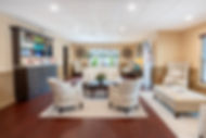 Elegant waiting room with plush seating, dark wood floor, product display cabinet.