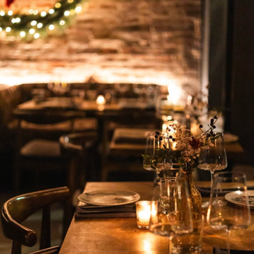 Cozy restaurant table set with wine glasses and wreath.