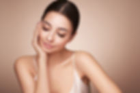 Serene young woman with clear, radiant skin touching her smooth cheek.