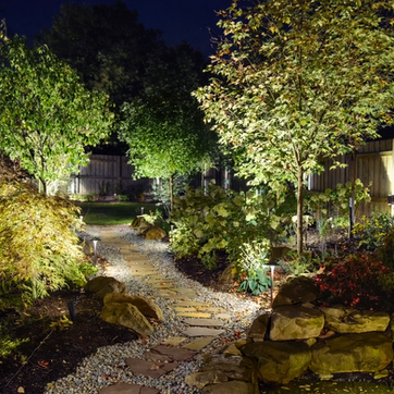 Winding stone path garden illuminated by landscape lighting at night. Residential landscaping near me| Down To Earth Landscaping | Jackson New Jersey, USA (732) 833-7702