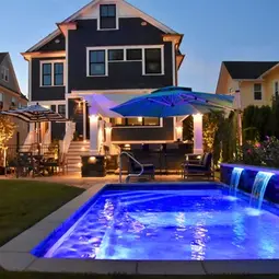 Modern backyard with illuminated pool, dark house, patio, at night. | Down To Earth Landscaping | Jackson New Jersey, USA (732) 833-7702