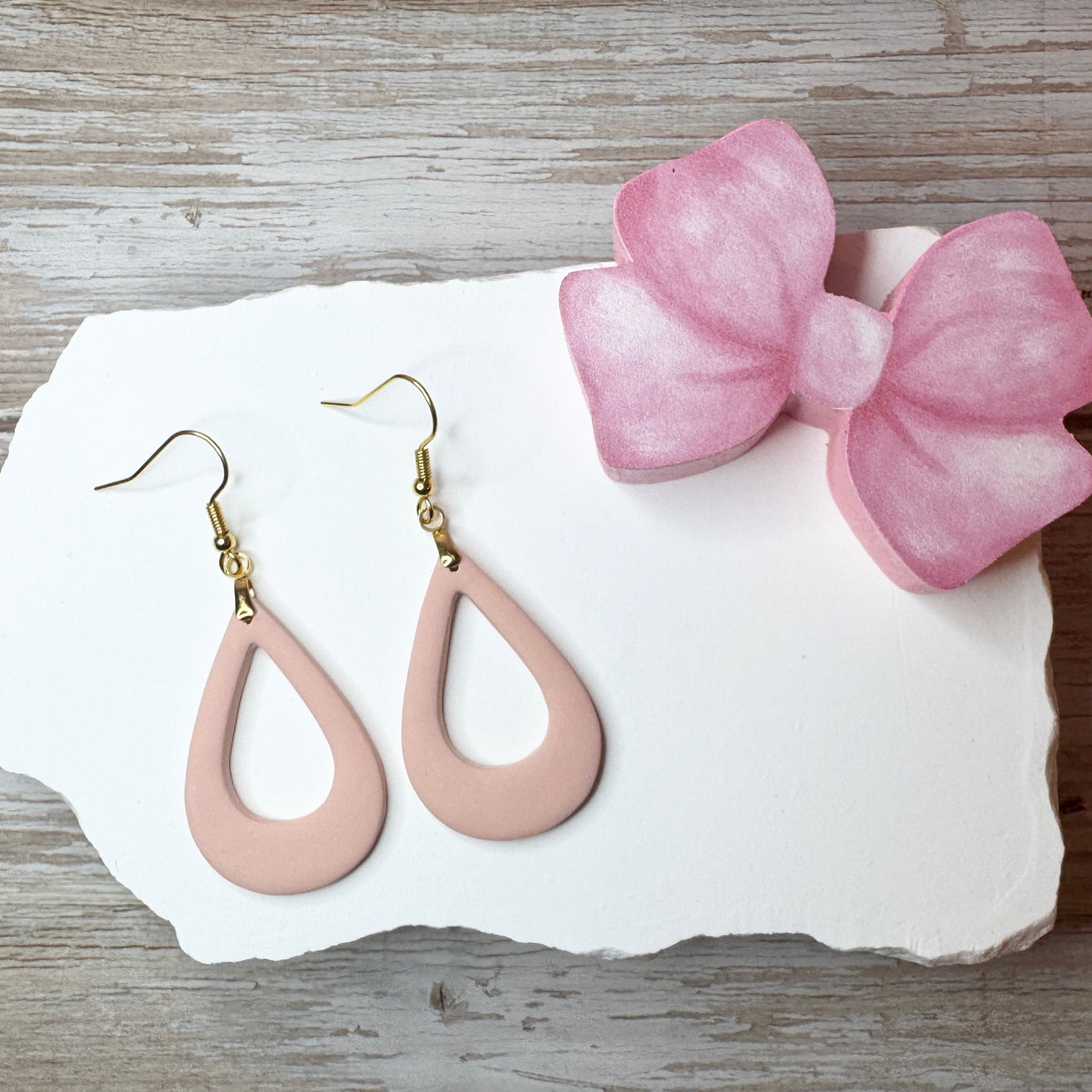 Fawn Poppyseed Elizabeth - Offset Tear Drop Polymer Clay Earrings on white stone with a pink bow