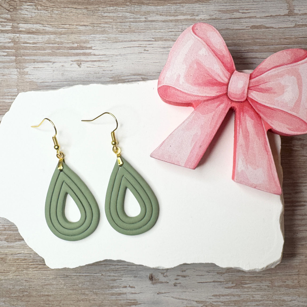 Elizabeth | Sculpted Polymer Clay Earrings (Moss) displayed on stone with pink bow.