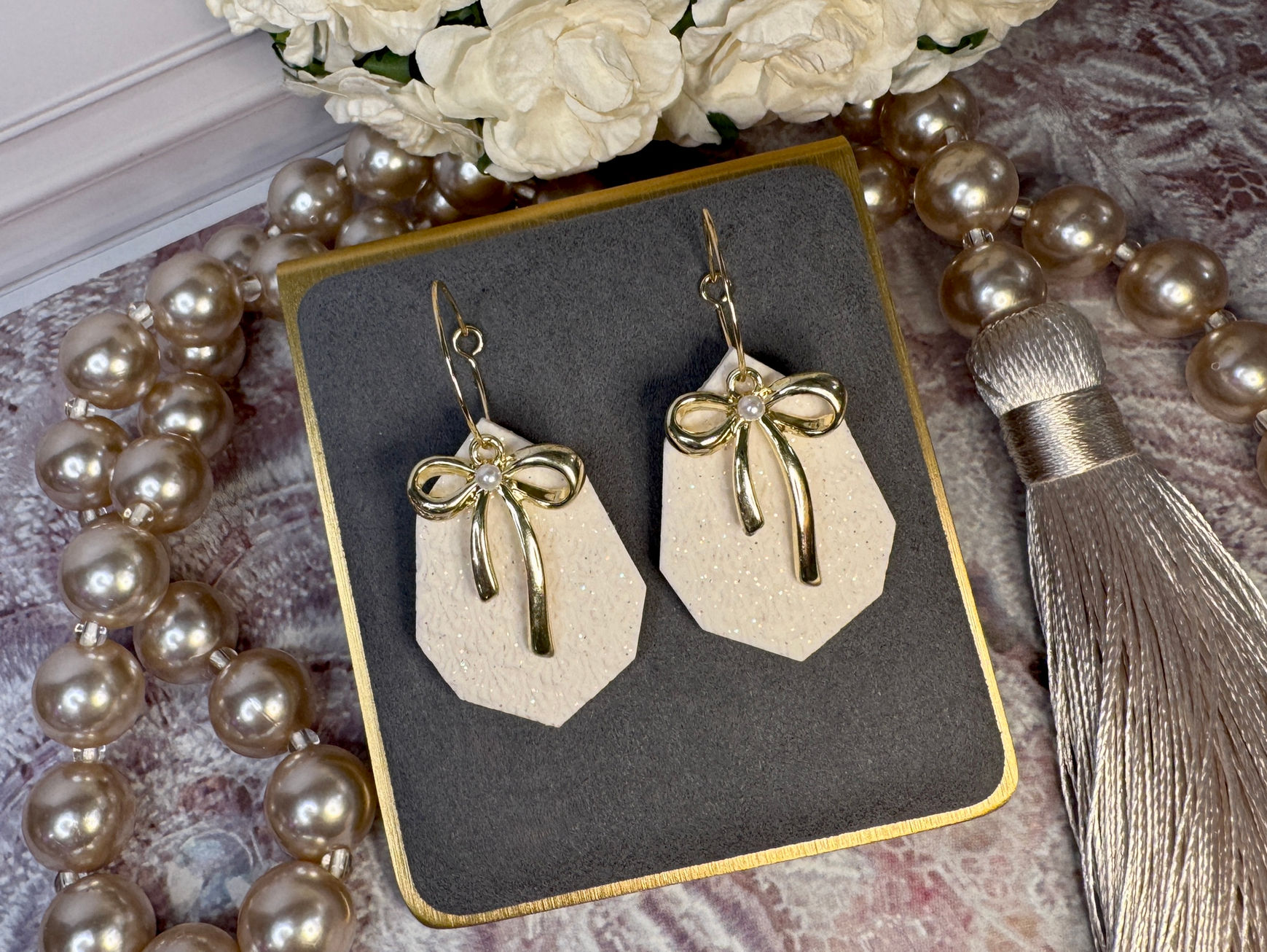 Golden Promise Bow earrings on white hexagonal drops