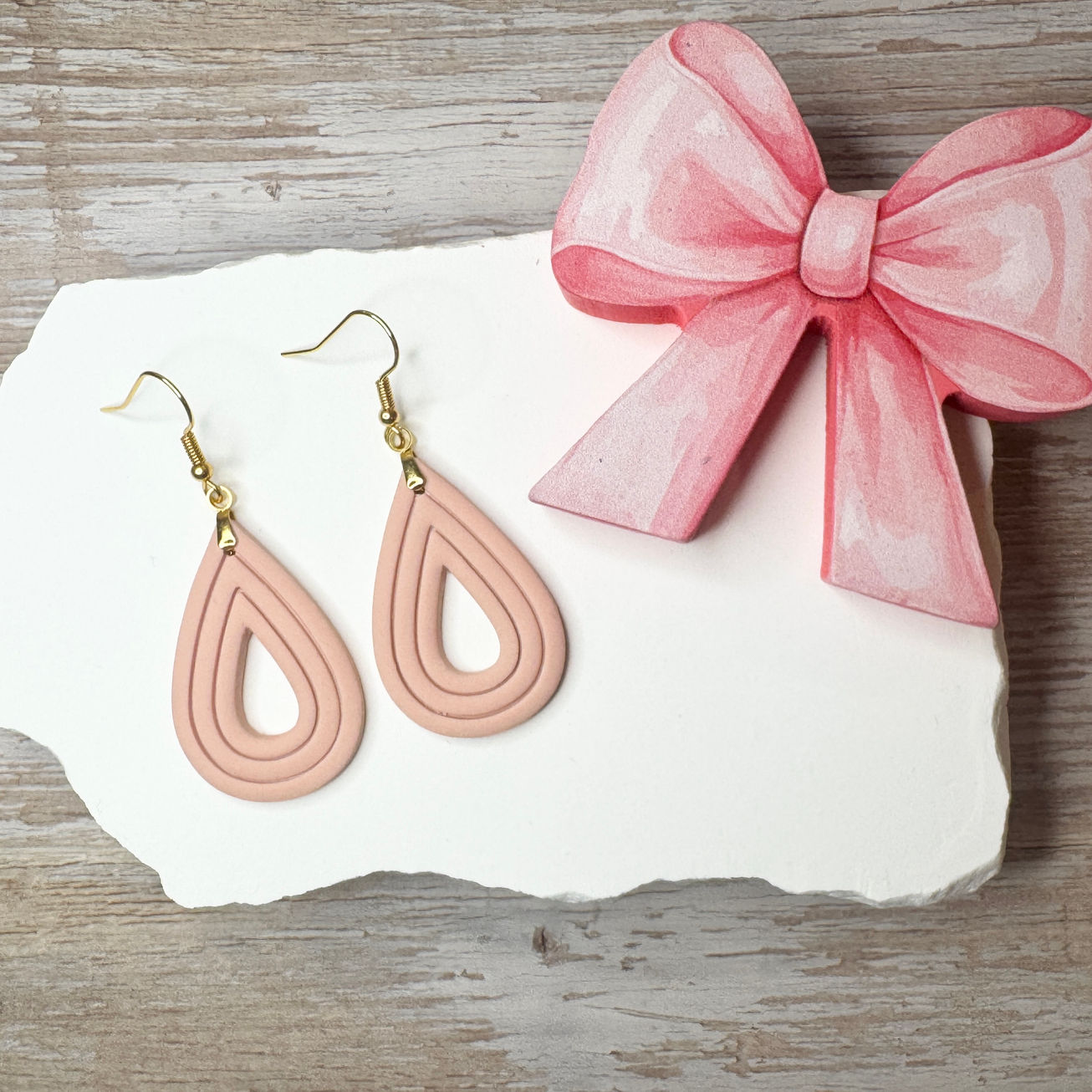 Elizabeth | Sculpted Polymer Clay Earrings (Fawn) displayed on stone with pink bow.