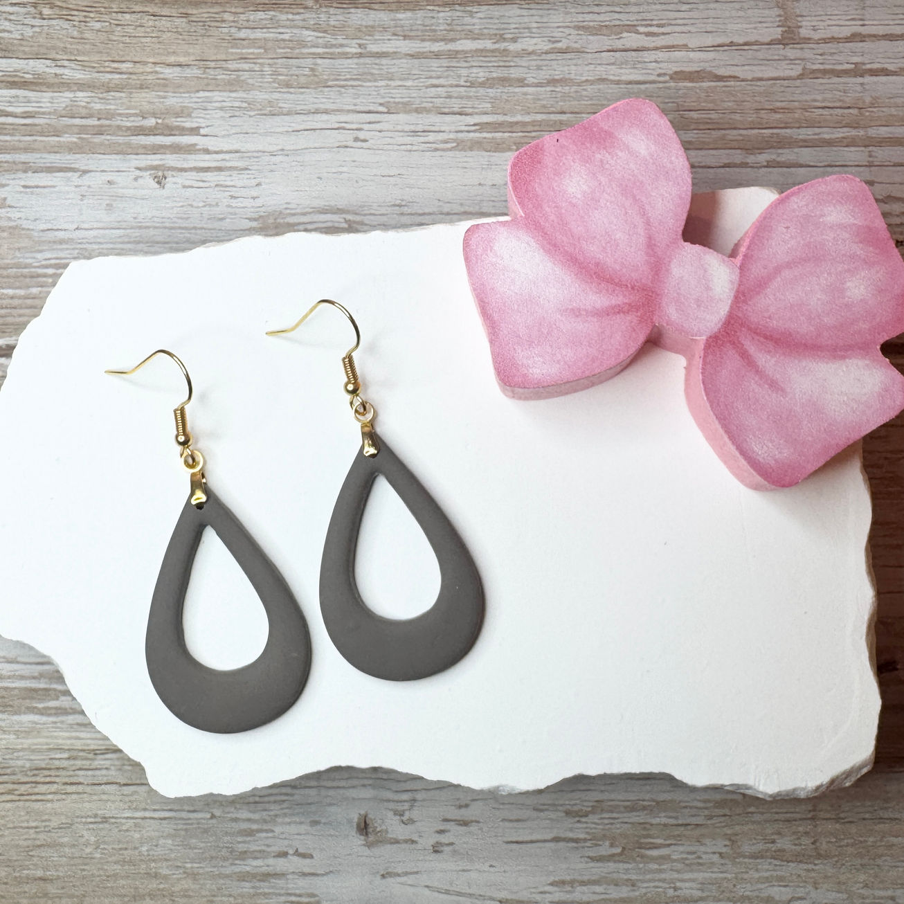 Stone Poppyseed Elizabeth - Offset Tear Drop Polymer Clay Earrings on white stone with a pink bow