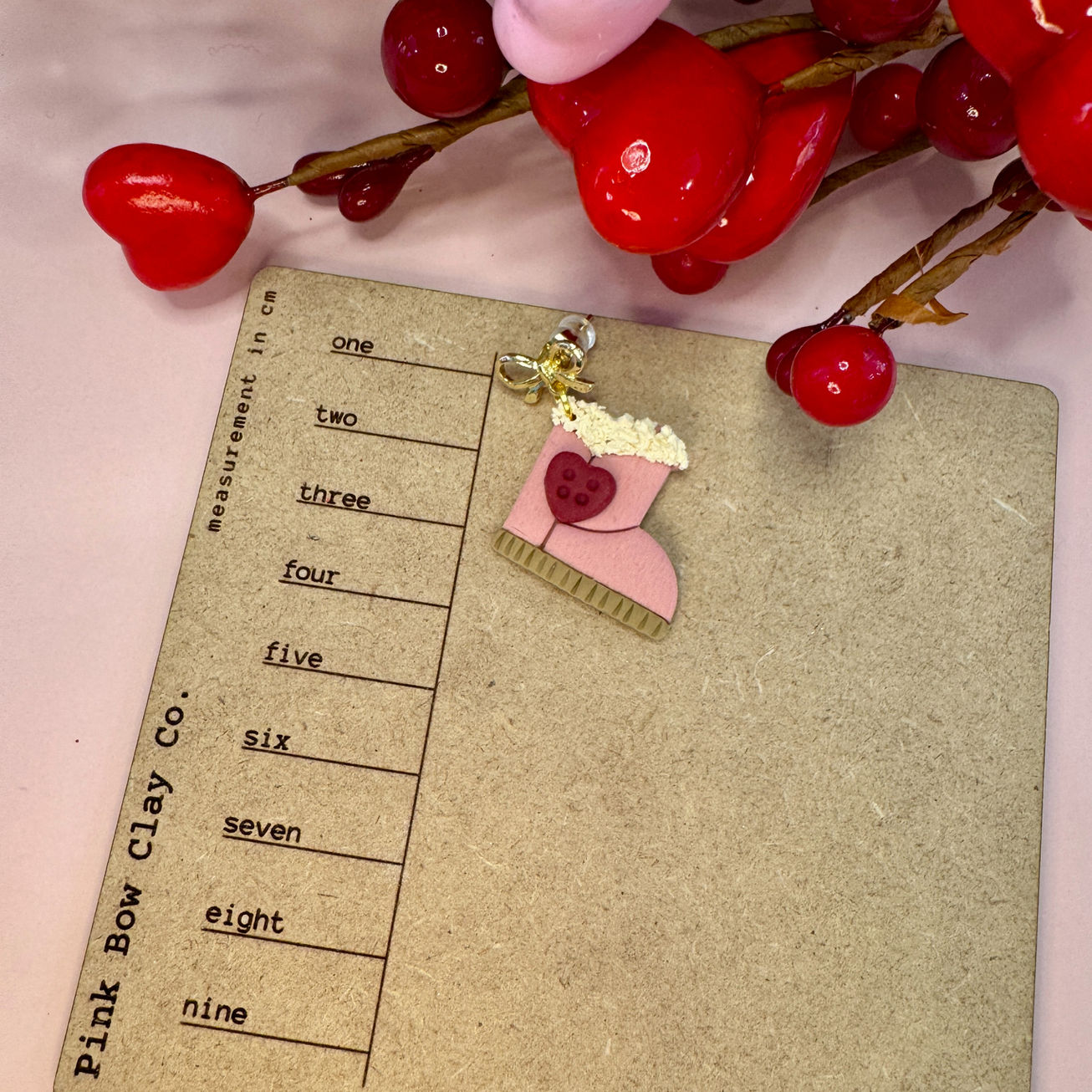 Pink Be Mine Boots clay charm on a measurement card.