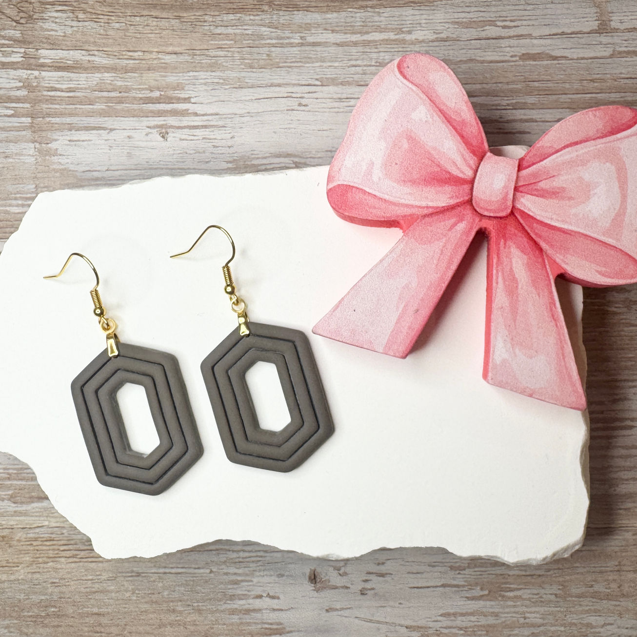 Stone Zelda geometric sculpted polymer clay earrings with gold-tone fishhook ear wires displayed with pink ribbon.