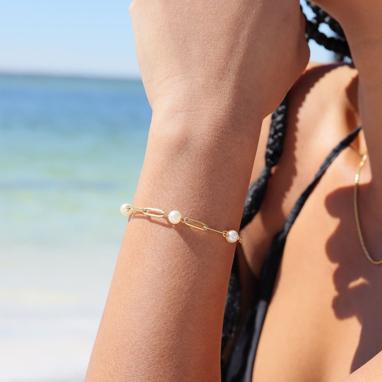 Women wearing gold station paperclip bracelet