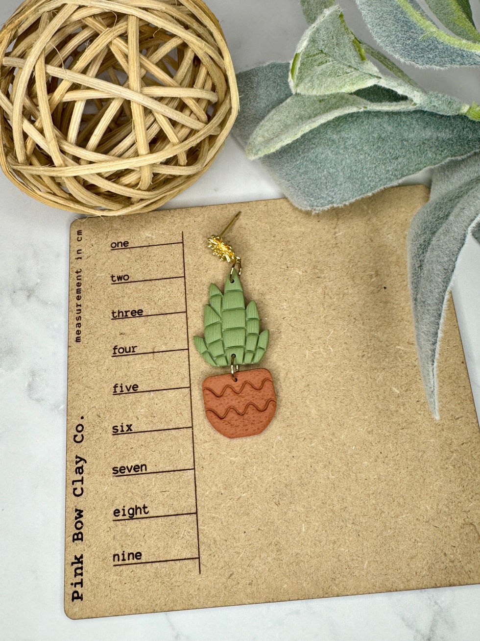 Terracotta Lila potted cactus clay earring on a ruler