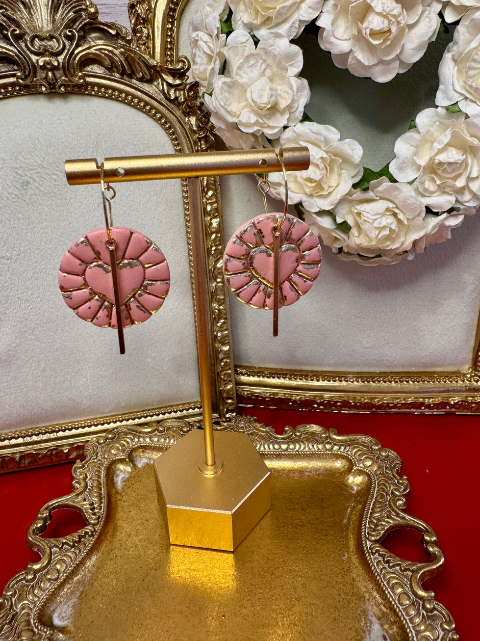 Pink Cupid's Heart Coin earrings displayed on a gold stand
