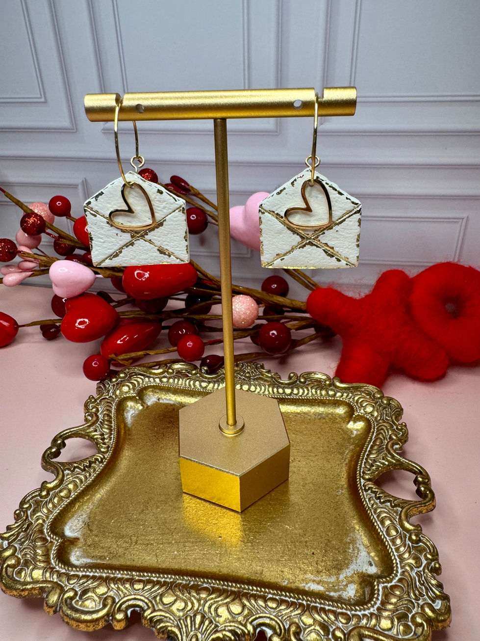 Golden love letter envelope earrings on a jewelry stand
