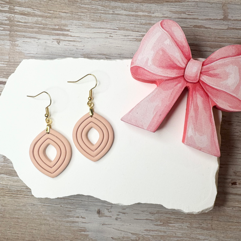 Clara | Sculpted Leaf Polymer Clay Earrings (Fawn) displayed on white stone with a pink bow