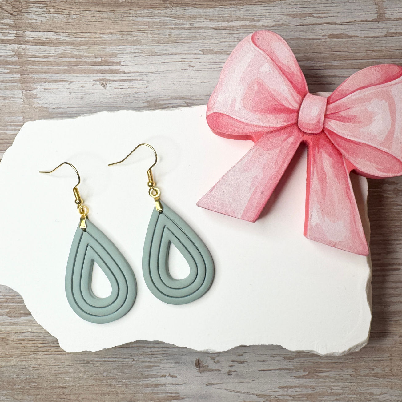 Elizabeth | Sculpted Polymer Clay Earrings (Seafoam) displayed on stone with pink bow.