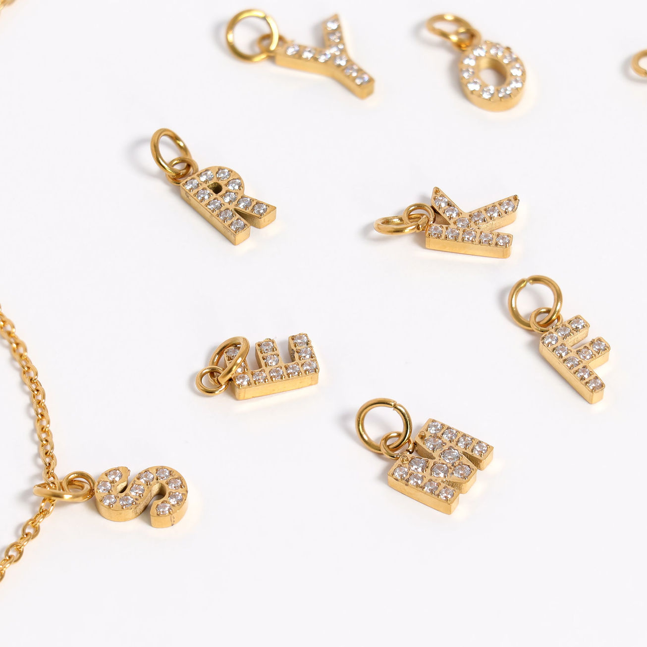 Pavé Letter Charms shown near chain necklace in gold