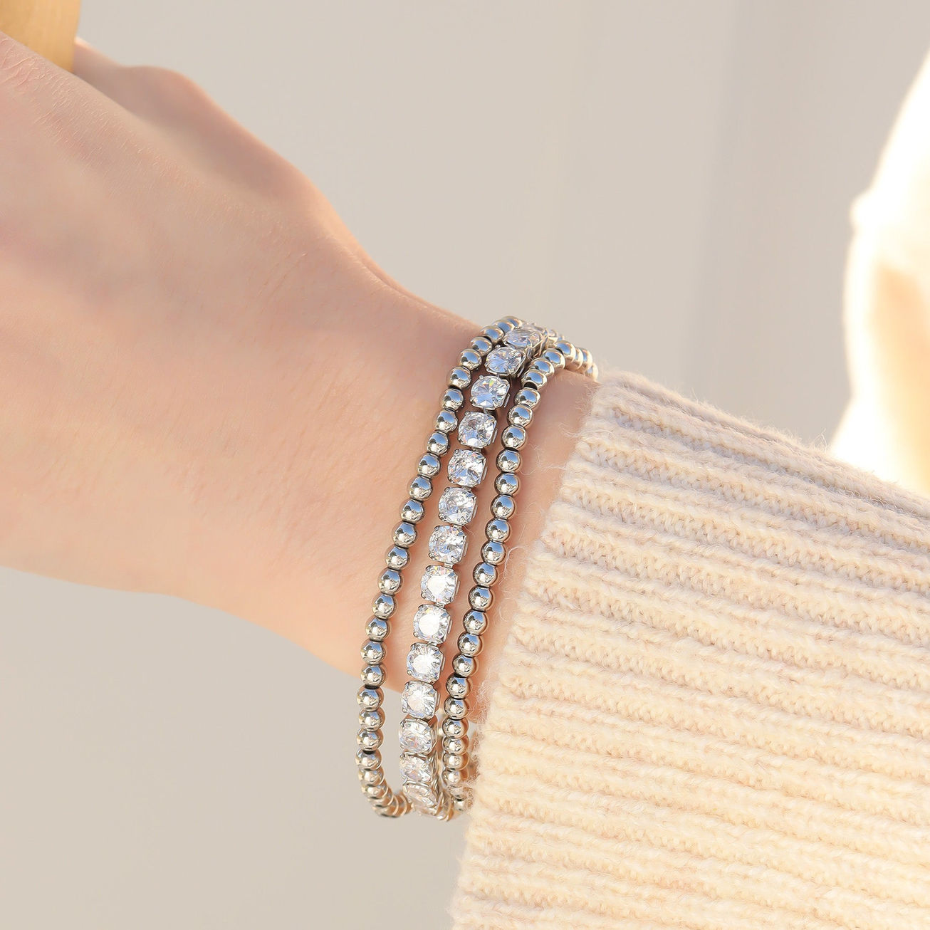 oman wearing a stack of polished stainless steel beaded stretch bracelets for an everyday layered jewelry look.