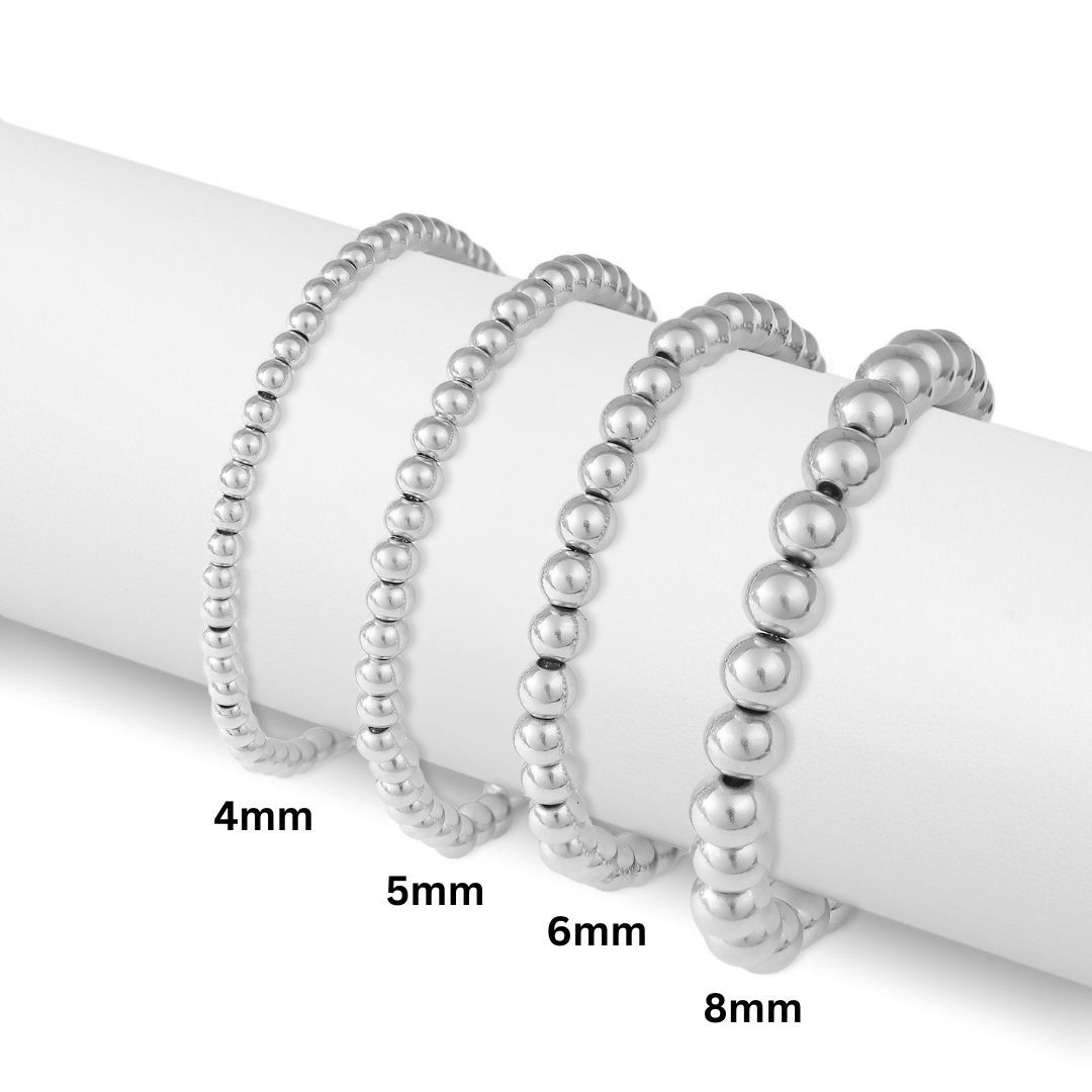 Stacked polished stainless steel beaded stretch bracelets in 4mm, 5mm, 6mm, and 8mm bead sizes.