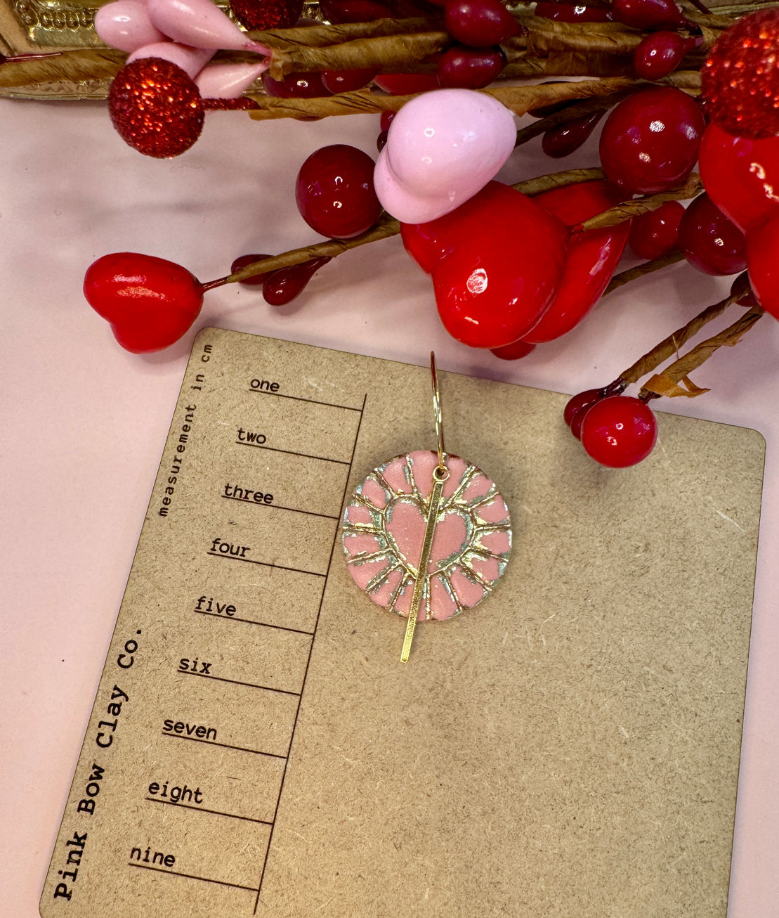 Heart-shaped Cupid's Heart Coin earring on measuring card.