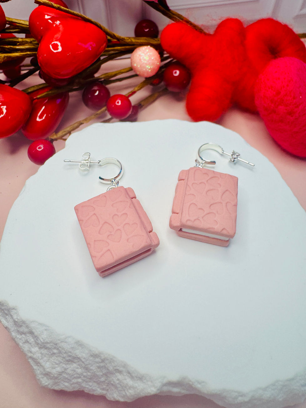 Pink Book of Love earrings with heart patterns on white stone