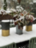 table, luminaria and a bucket of flowers covered with snow