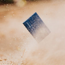 Smartphone Samsung projeté dans un nuage de poussière, illustrant sa résistance aux chocs et aux conditions extrêmes.