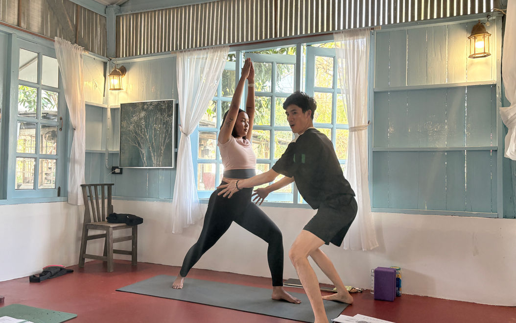 Student being taught alignment by a yoga teacher