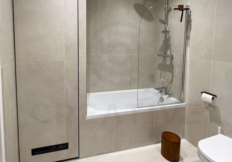 Modern bathroom with bath and tiled walls in London flat refurbishment