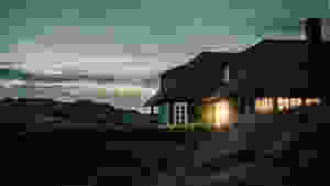 gray house with fireplace surrounded by grass under white and gray cloudy sky