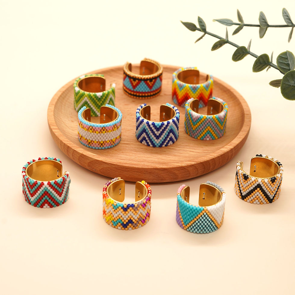 LANCUI's Bohemian Miyuki bead rings on a wooden tray with a neutral background and plant leaves. Bright, geometric patterns create a vibrant look.