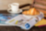 Coffee, croissant and magazine at outdoor patio cafe