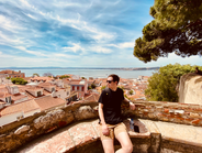 Man looking over a city with red roofs and a bay