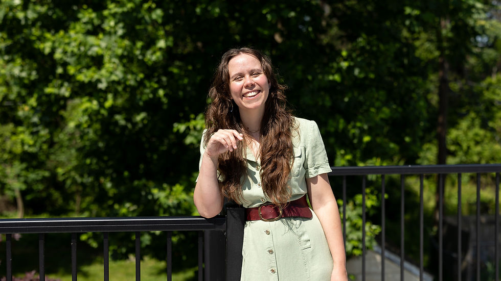 Erin, a therapy in Baltimore professional, smiling in a green dress with trees in the background