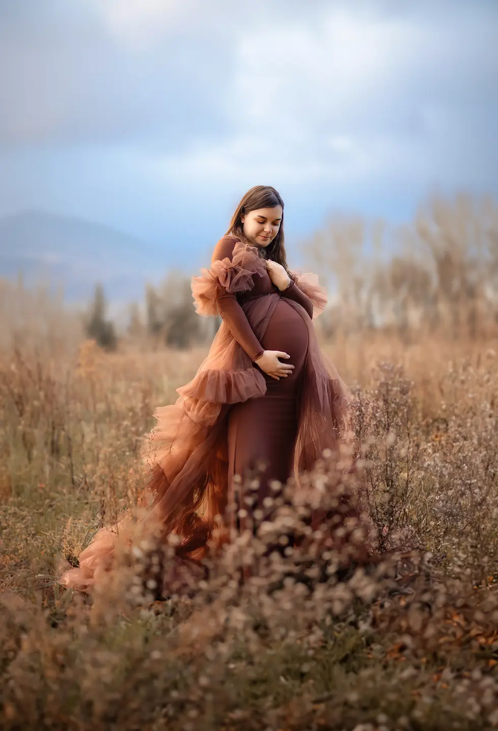 Séance photo grossesse féerique, future maman regardant son ventre avec douceur, décor naturel près d’Agen.