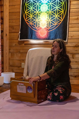 Dawn seated playing the harmonium and singing during a sound bath