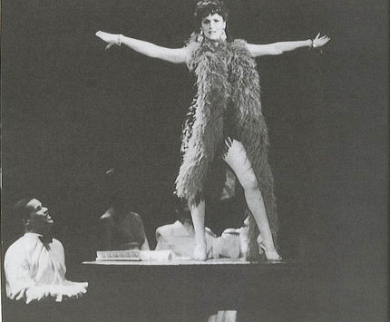 Nicola is performing 'Man Wanted' in the musical Copacabana. She is wearing a beautiful dress with a long feather bower wrapped around her neck. She's is stood on a Piano singing, accompanied by Gary Wilmot playing the role of Tony 