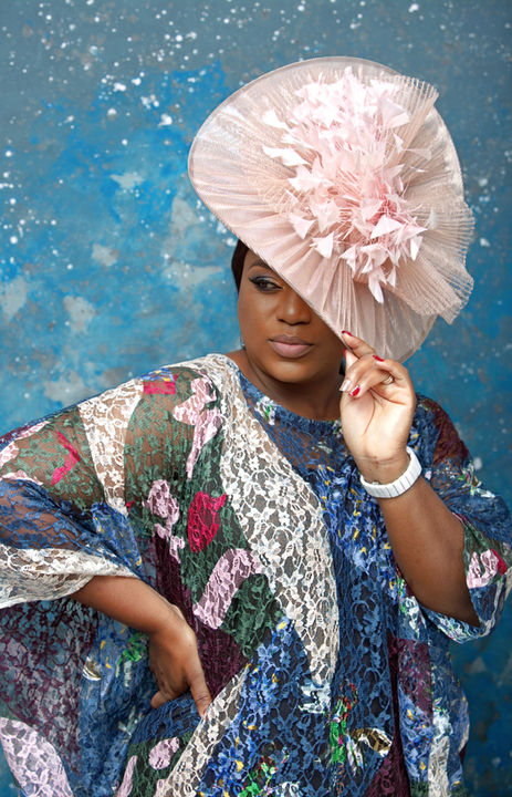 Glamorous model posing confidently during a high-fashion photoshoot, wearing an elegant designer outfit with dramatic lighting and a stylish backdrop.