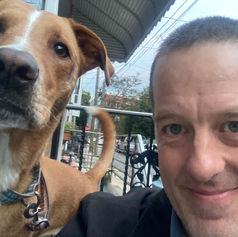 A man takes a selfie with a brown and white dog