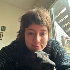 A dog walker snuggles with a black dog