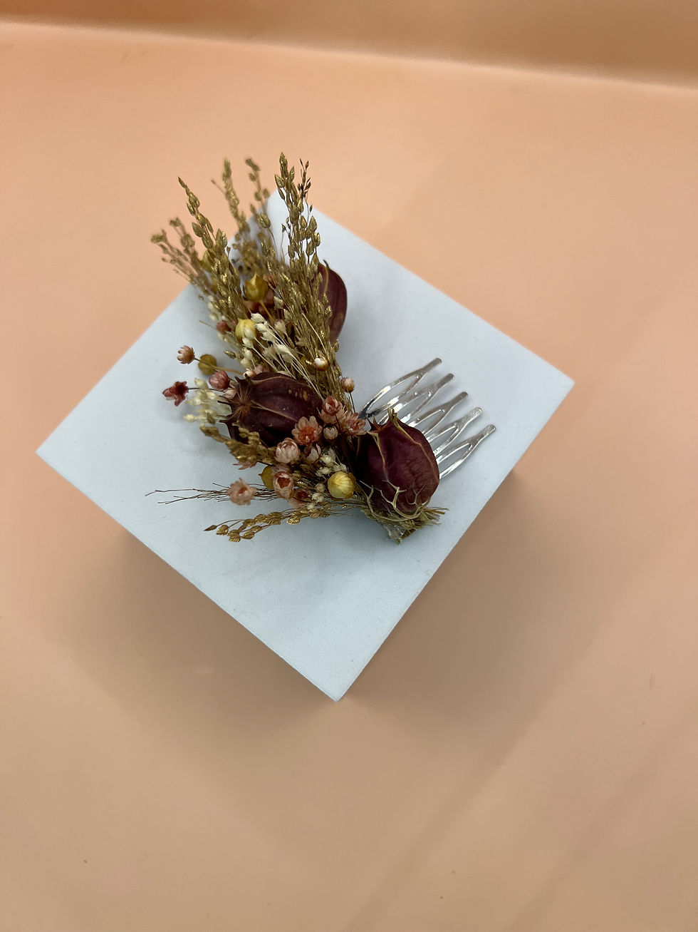 Miniaturbild: Auf einem quadratischen Podest ist der Haarschmuck aus Trockenblumen so präsentiert, dass man den Steckkamm gut sehen kann