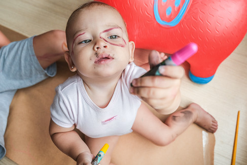 criança olhando para a canetinha, com o rosto todo pintado em Curitiba