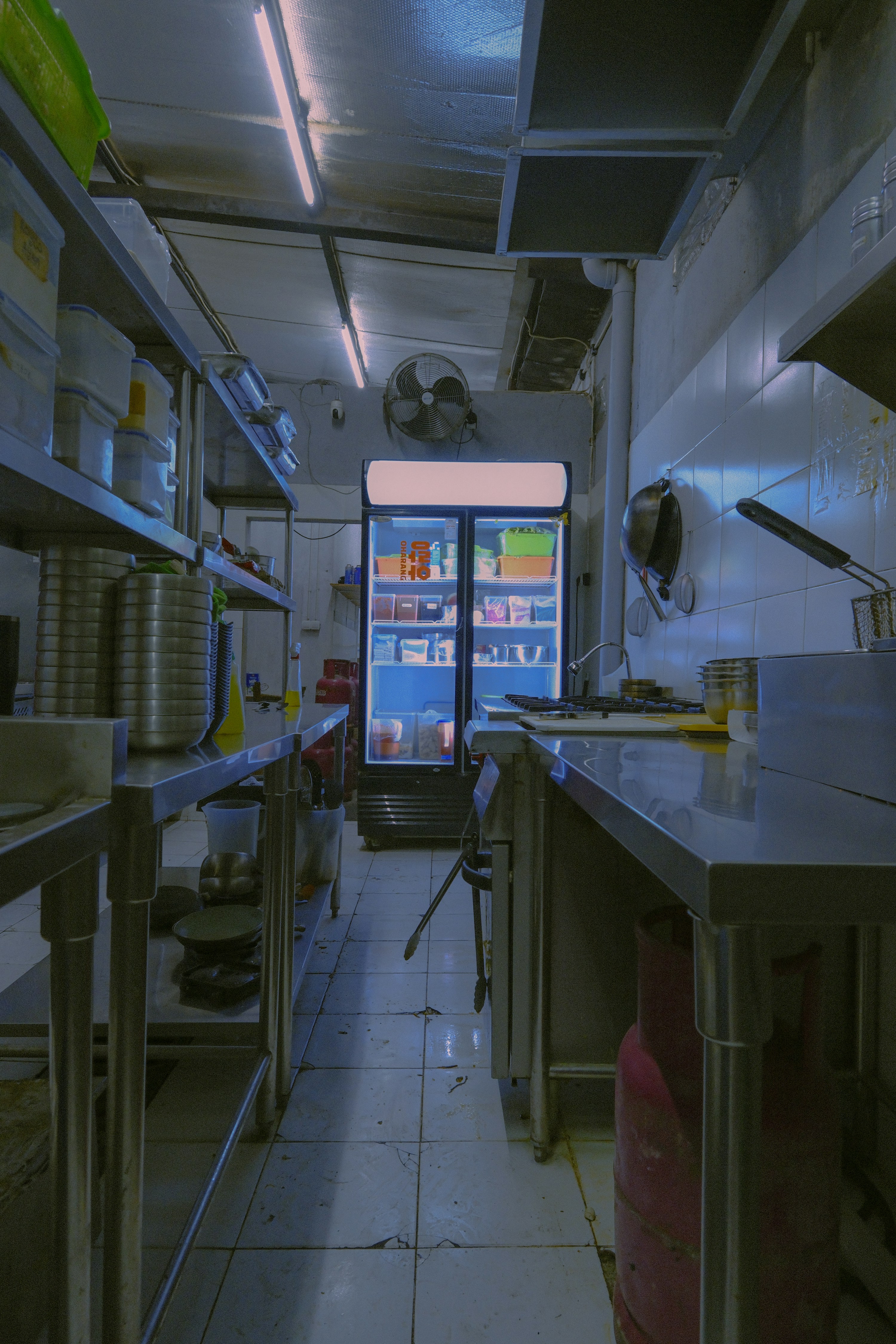 Stainless steel restaurant kitchen with an illuminated commercial refrigerator