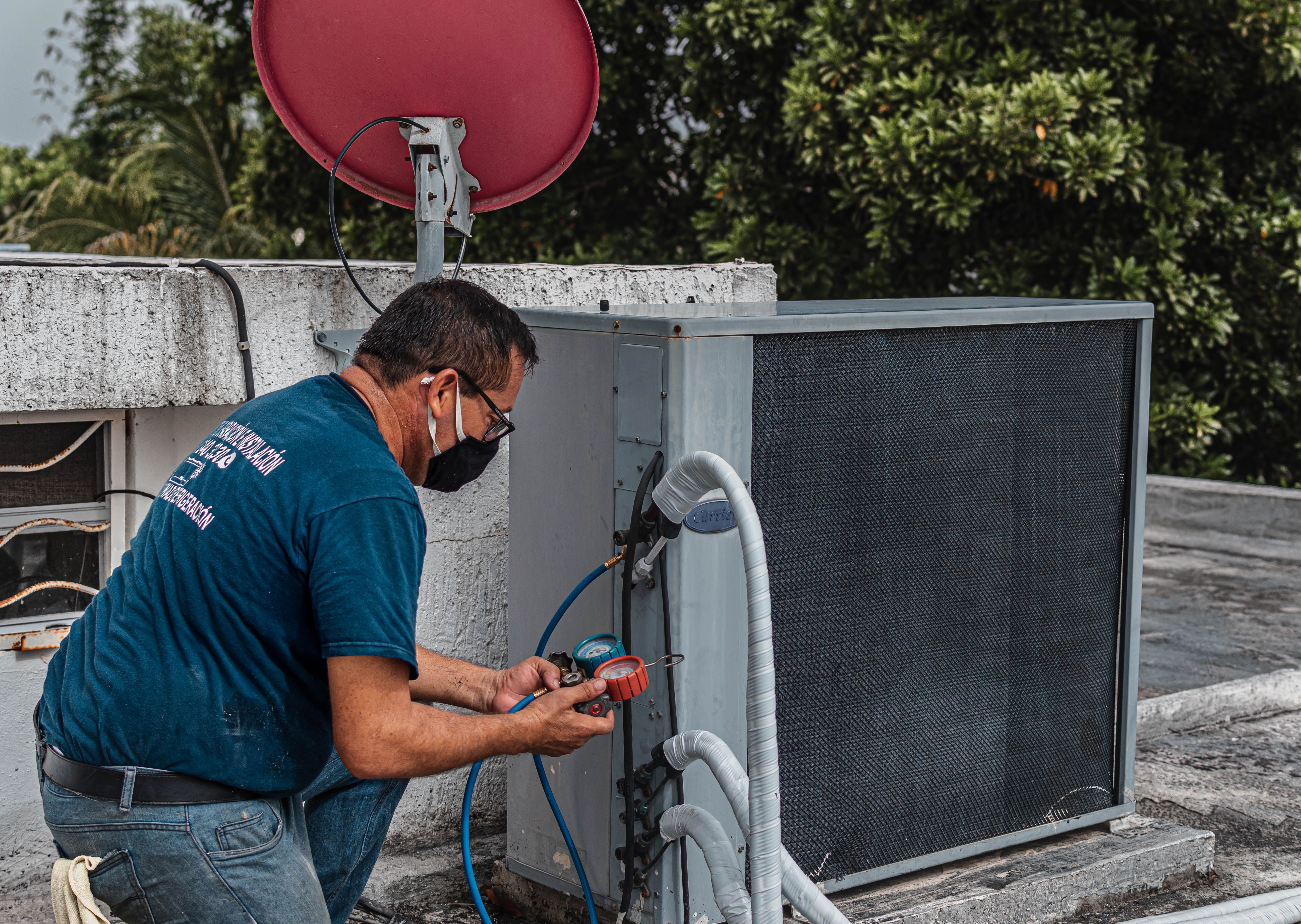 Technician checking an outdoor air conditioner with refrigerant gauges