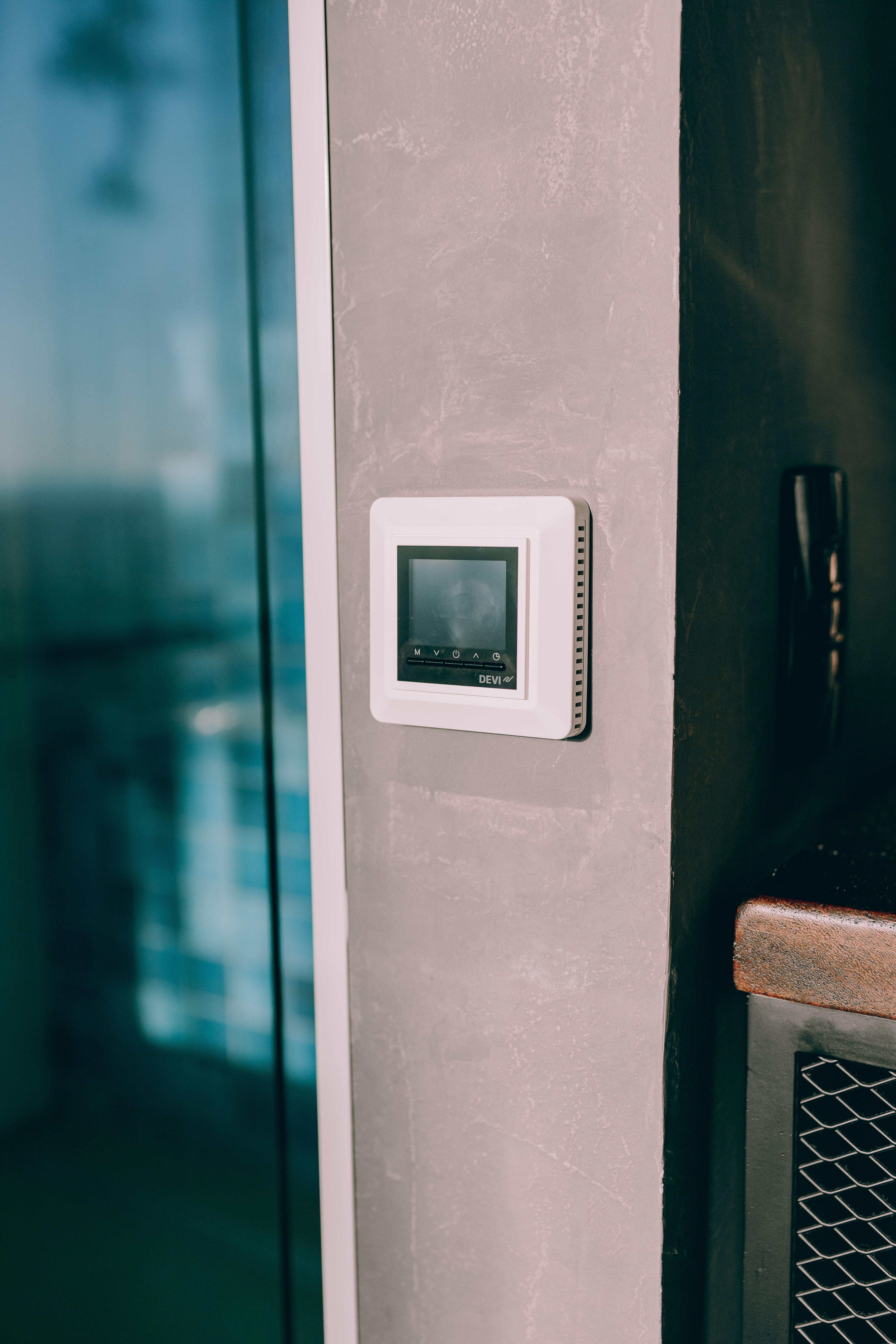 Wall-mounted digital thermostat beside a window