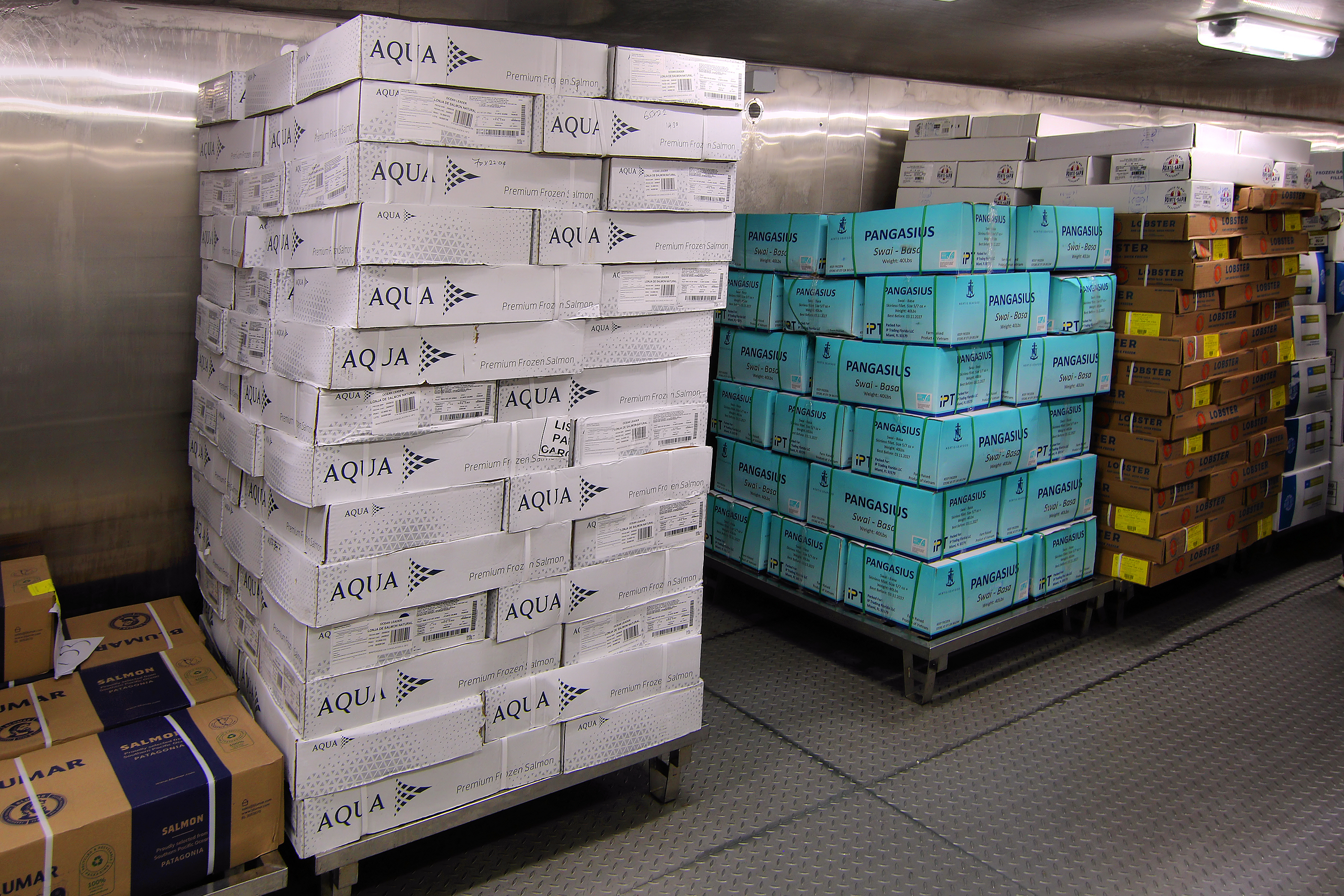 Food cartons stored on racks inside a stainless-steel walk-in freezer