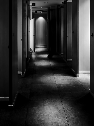 Black-and-white hallway with open doorways and deep shadows, suggesting tension and moral consequence
