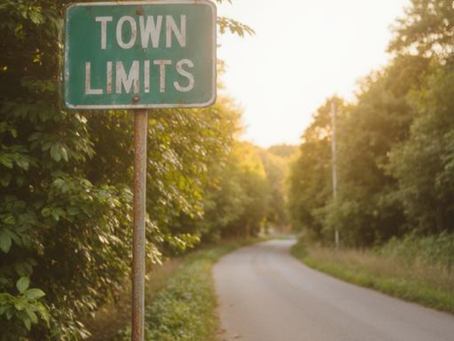 Town limits sign beside a curving rural road, suggesting belonging and social boundaries in Southern crime fiction