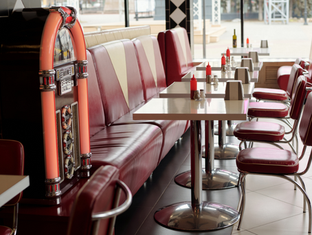 Empty diner booths and jukebox in a small-town café, suggesting gossip and selective silence